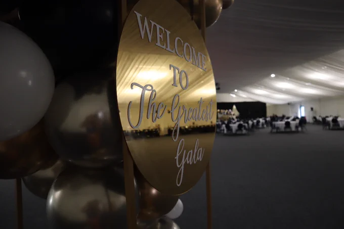 "Welcome to the Greatest Gala" sign with balloons