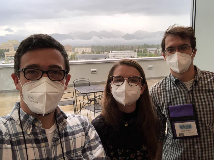 PI Daniel Jones, grad student Brannan Cliver and research assistant Reid Selby standing together, masked with mountains in the background (in convention center in Anchorage, Alaska)