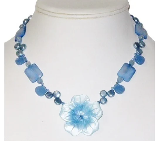 This is a photo of a necklace with a pastel blue mother of pearl flower pendant.  This necklace also consists of stunning freshwater pearls, mother of pearl beads and faceted glass and jade beads.  It's perfect to jazz up your favorite summer outfit.  It measures approximately 18 inches. You can buy it on our website at www.angiesheldesigns.com 