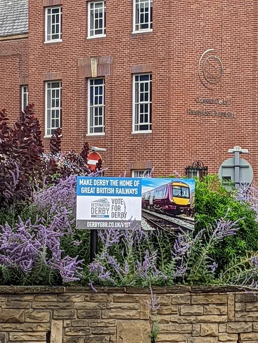 Vote for Derby GBR poster on roundabout outside brick building.