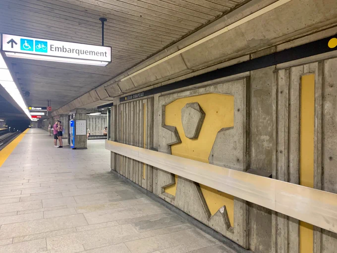 Concrete walls with abstract yellow murals in the shape of a human in a carrying stance, meant to depict the Titan Atlas