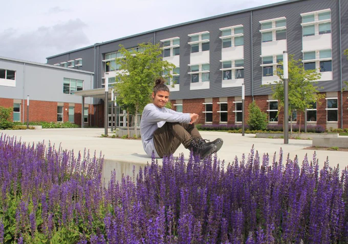 Student in HHS south courtyard by purple flowers