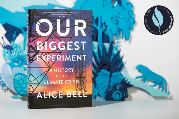 to the left of the picture, the front cover of a book - Our Biggest Experiment, a history of the climate crisis by Alice Bell - with some blue paper cut outs of animals and trees in the background and a logo for the Wainright Prize in the top right hand corner