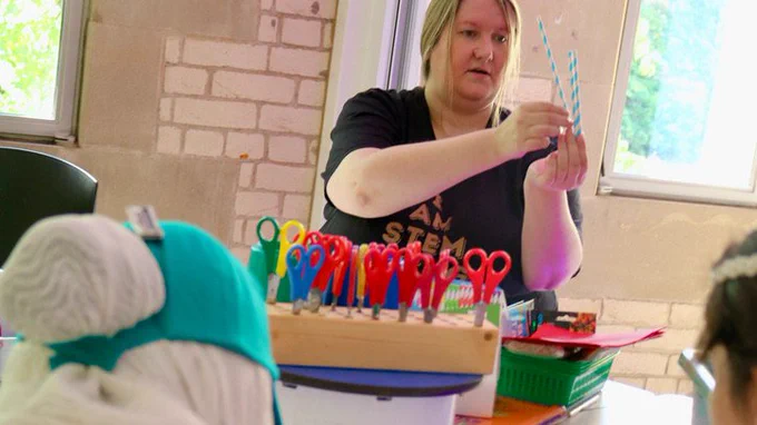 An engineering showing the young people how to cut the straws for an activity 