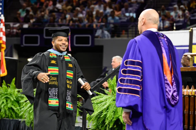 A graduate smiles as they walk across the stage at Clemson graduation. 
