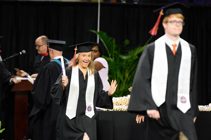 A graduate smiles as they walk across the stage at Clemson graduation. 