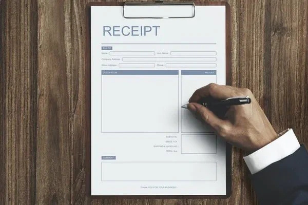 hand writing on charitable tax receipt on clipboard