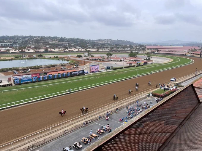 A view from up high of horses and jockeys warming up on the race track.