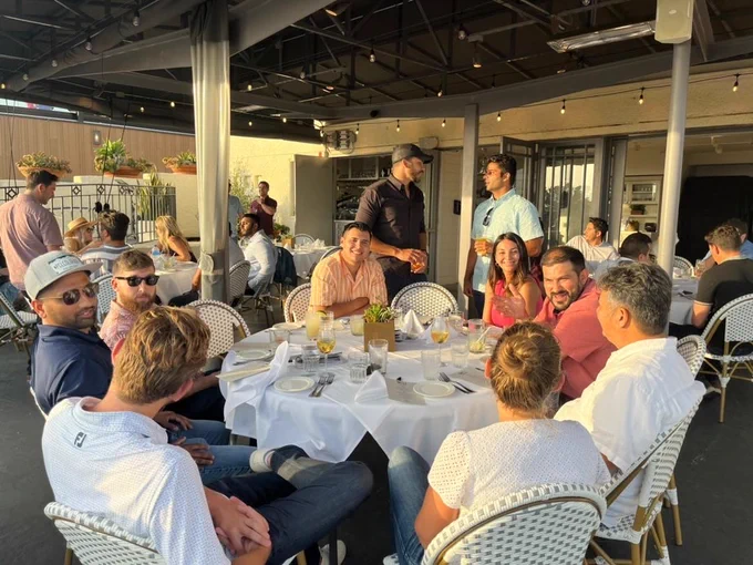 A group of people enjoying food and talking at a nicely set table.