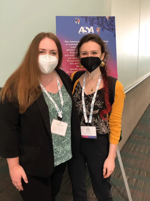 Baylee and Reilly stand in front of a colorful sign in the LACC at ASA 2022