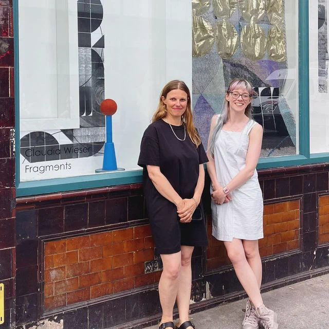 Claudia and Hannah smiling in front of CPT window gallery.