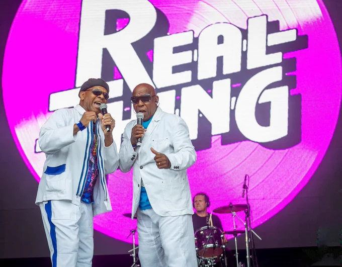 image of two members of the real thing performing live on stage