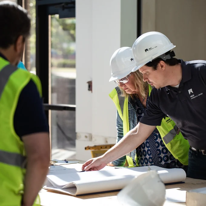Foundation staff and renovation vendors around a table reviewing building plans