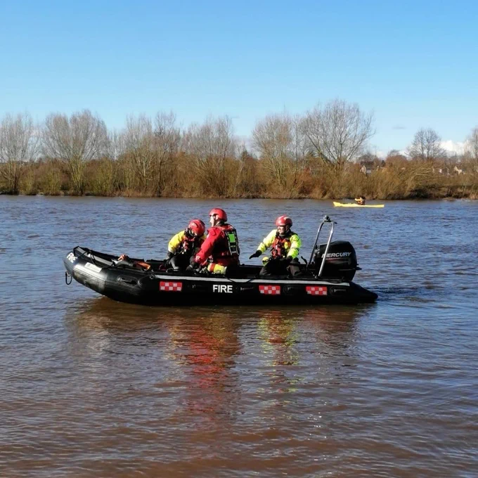 Firefighters in the fire service boat on the water.