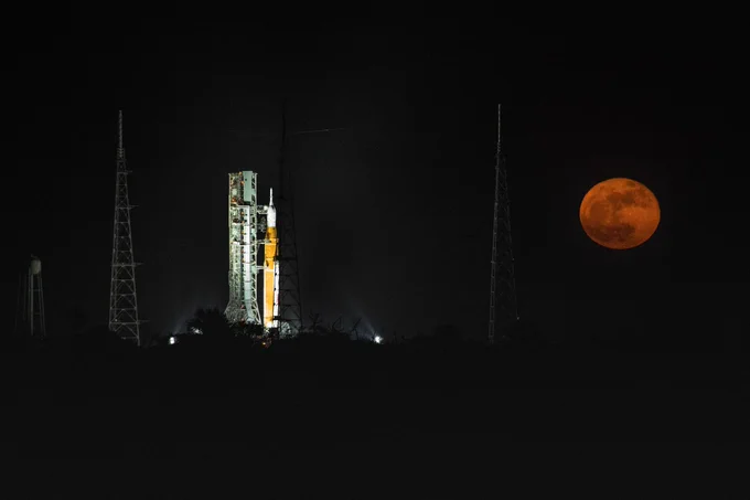 The SLS rocket on Pad 39B at NASA's Kennedy Space Center with a full Moon in view.