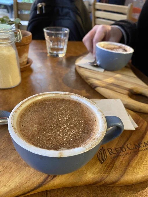 Cup of hot chocolate on a wooden board with the Red Cacao logo on it