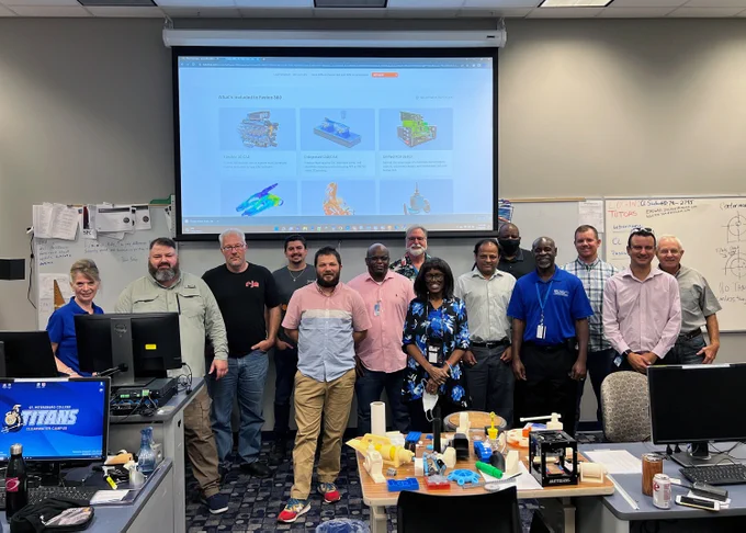 A group of SPC employees huddle together for a picture in front of a projector screen in a computer lab. 