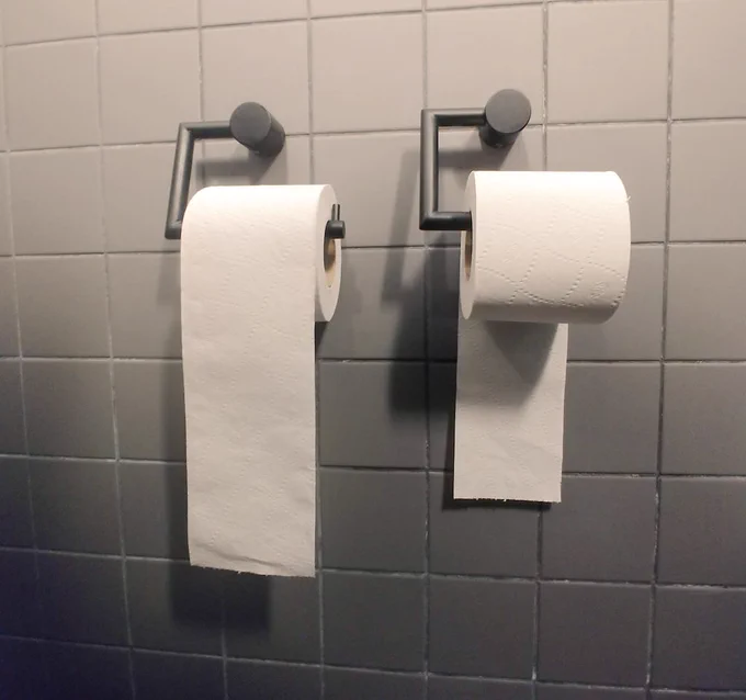 Two roles of toilet paper. One oriented under, the other over. 