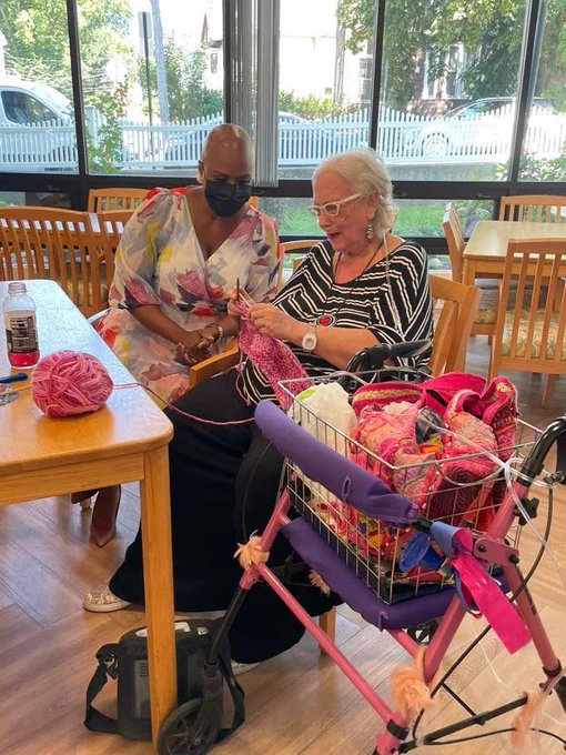 Congresswoman Pressley joins an elderly woman as she knits at Properzi Manor in Somerville.