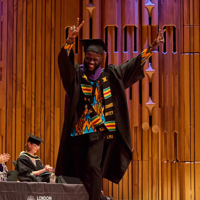 Graduate walking across stage holding up the peace sign