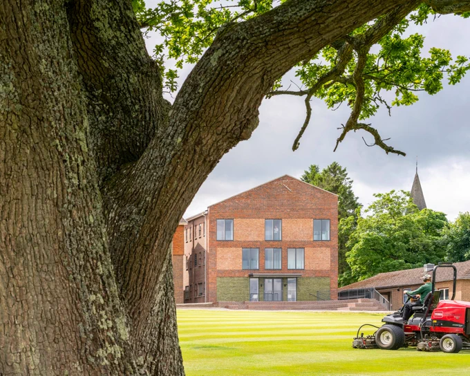 A tree frames a view of a new music school building in Mayfield. Complementary brick tones modernise a pre-existing façade while the interiors have been completely refurbished to provide state of the art practise and performance rooms. 