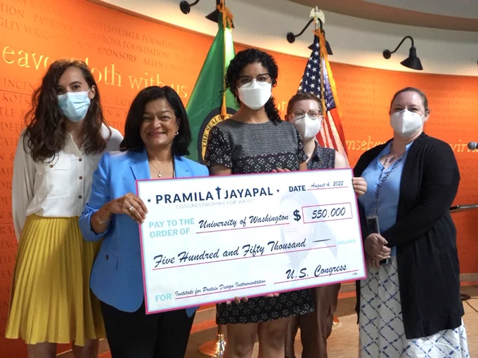 Congresswoman Pramila Jayapal hands an enlarged check for $550,000 to a team from the University of Washington Institute for Protein Design. The funding will support the purchase of advanced research equipment. 