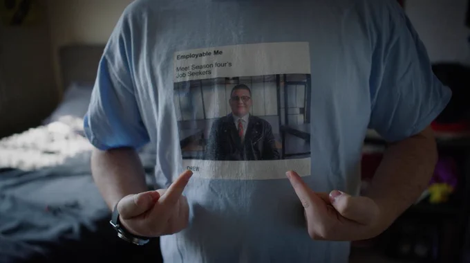 Drew is wearing a sky-blue t-shirt with a photo of him from Season 4 of Employable Me. The text on the t-shirt reads, “Employable Me.
Meet Season four's job seekers. Drew.”