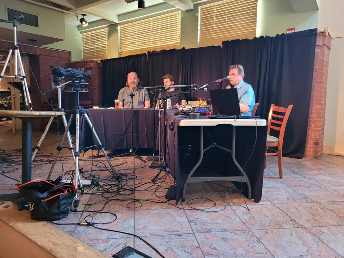 Matt, Mike and Adam Loux sit at two tables on stage