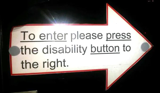 A white arrow on a black background with text on it which says "To enter please press the disability button to the right"