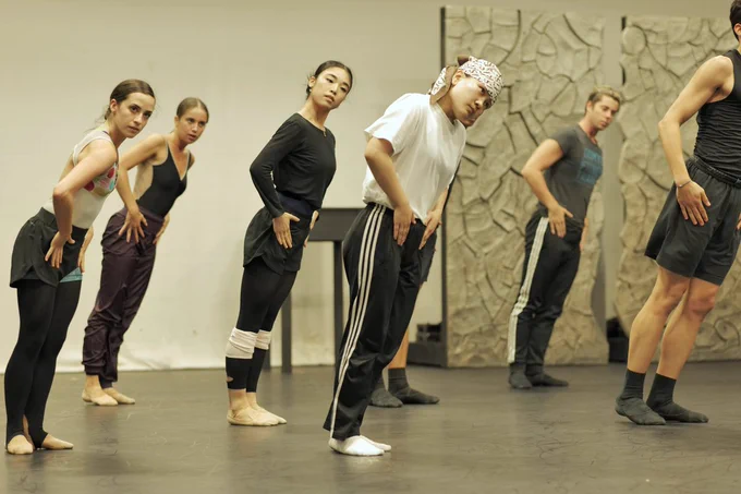 Northern Ballet dancers are in rehearsal. They are stood facing the camera learning towards the right, with their hands on their hips. Photo by Mthuthuzeli November.