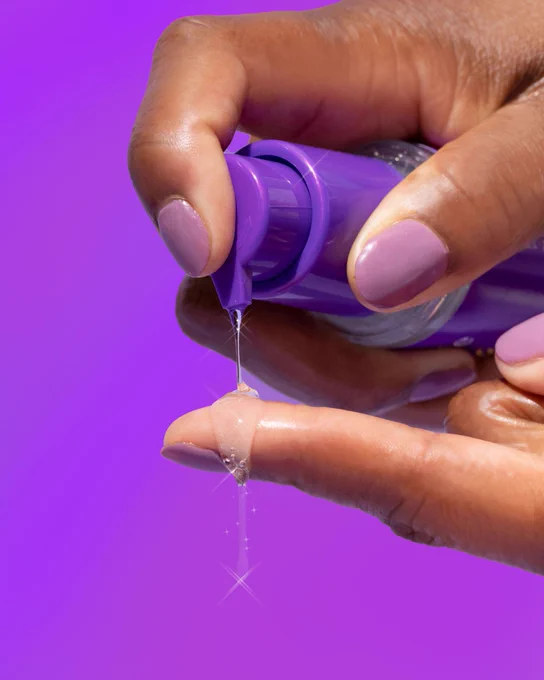 Aussie Haircare Miracle Oil dripping onto finger with purple background and sparkle effect