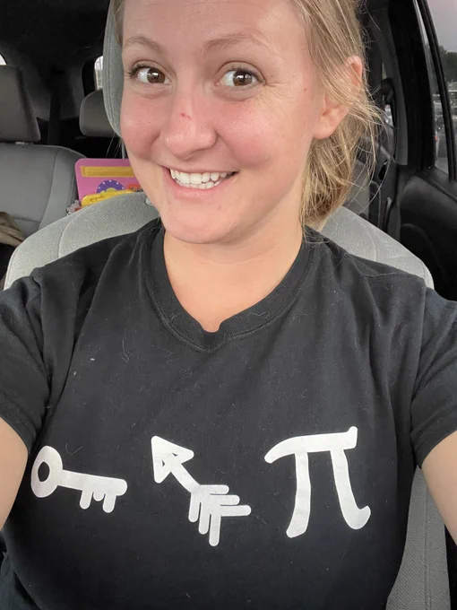 A selfie of Profe Szczesny wearing a black T-shirt with the following white images across the chest: a key, and arrow, the pi symbol.