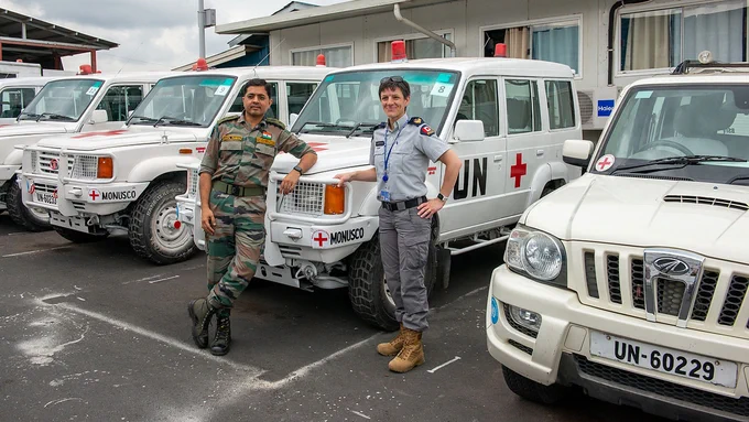 A Canadian woman police officer and an Indian officer stand outside in front of UN ambulances in the Democratic Republic of the Congo.
