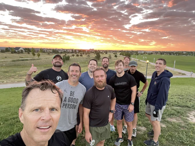 Group of men with sunrise behind them.