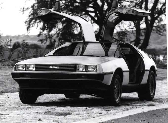 B&W photo of a DeLorean car with its winged doors fully open.