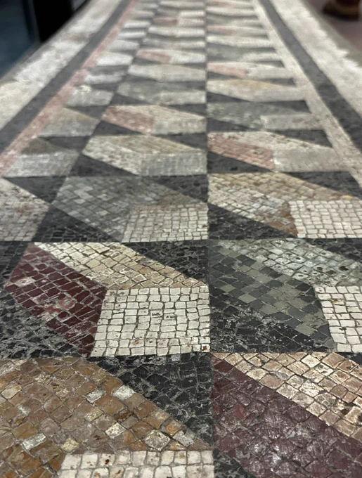 View from floor level along a mosaic with alternate yellow, red and green sided boxes represented in perspective with white ends