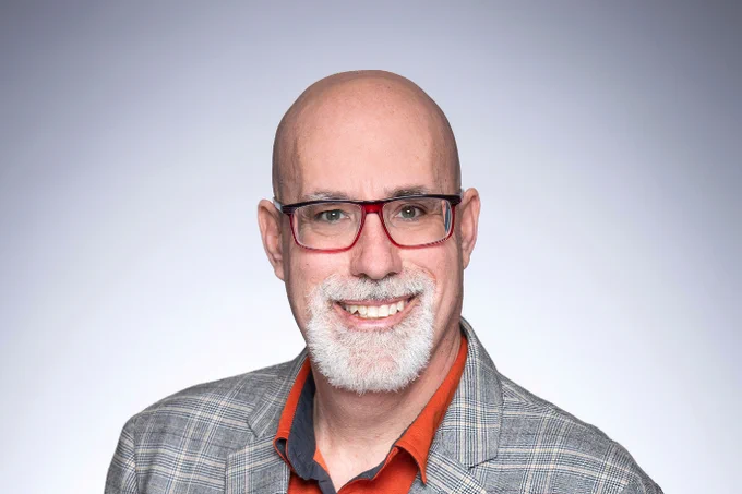 Professor Dionne wearing glasses and smilling.