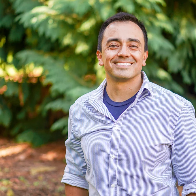 A photo of assistant professor of media studies Diego Cortés standing in front of a tree.