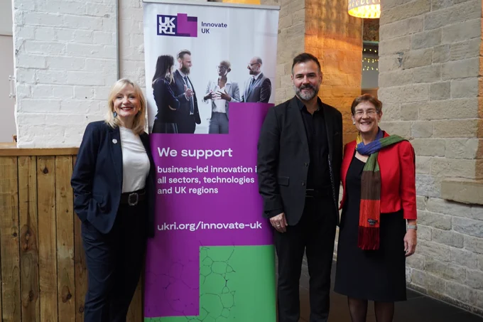 Tracy Brabin is stood next to a UKRI pop up banner smiling to camera. At the other side of the banner stand a man in a black suit and Cllr Scullion. They are also smiling to camera. 
The pop up banner reads "we support business-led innovation in all sectors, technologies and UK regions. ukri.org/innovate-uk"