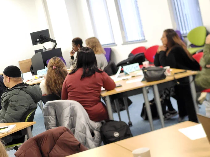 VCS community research champions sat around table listening to presenter at training workshop