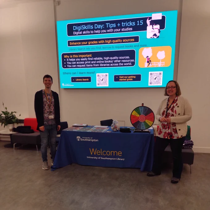 DigiSkills Day in Hartley Foyer. There are Tips and Tricks on the big screen-this tip talks about how you can 'Enhance your grades with high quality sources'. Staff members are standing by the table and the spin the wheel and prizes.