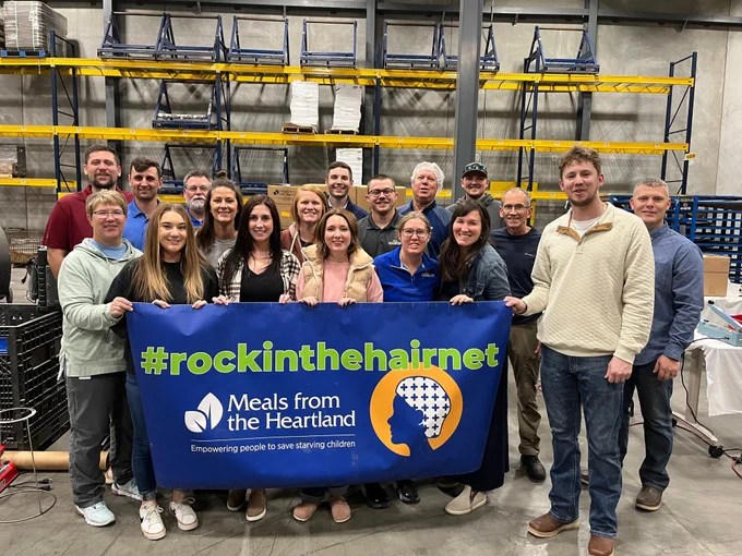 All the employee-owners who volunteered with a big Meals from the Heartland banner that says #rockinthehairnet.