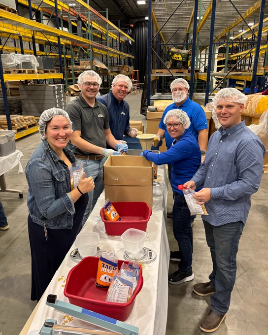 Six employee-owners packing meals in the warehouse.