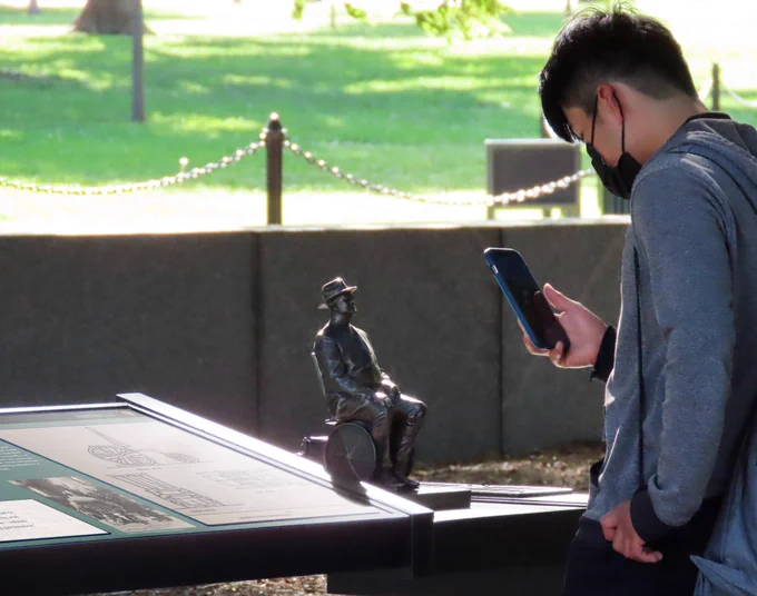 A visitor wearing a face mask takes a photo of the new FDR tactile. 