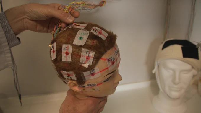 A person applying sensors to a mannequin head.