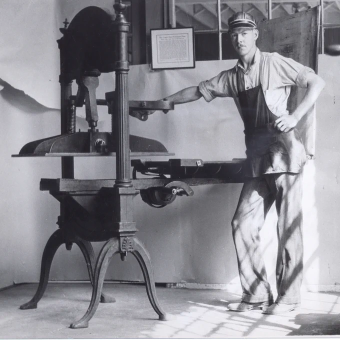 A man stands beside the historic Washington handpress that lives in Allen Hall at the University of Oregon circa 1955. 