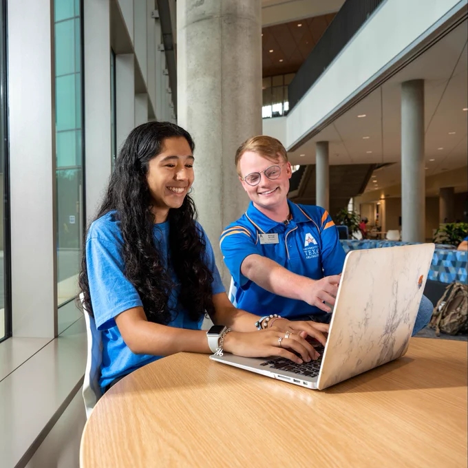 A male UTA Go Center team member helps a female student choose classes.
