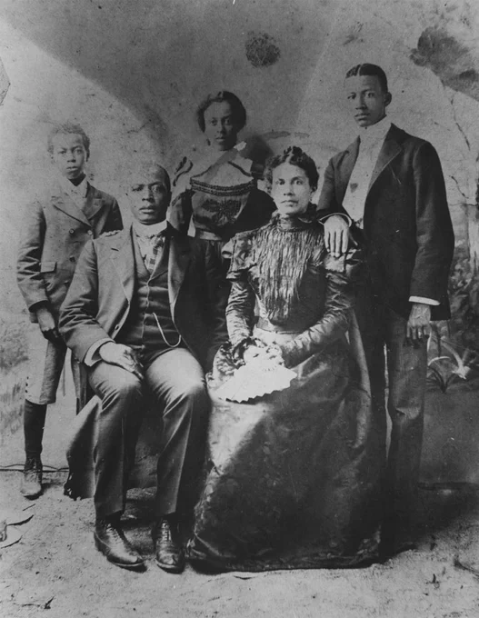 Ish parents seated in front and children standing behind them for family portrait
