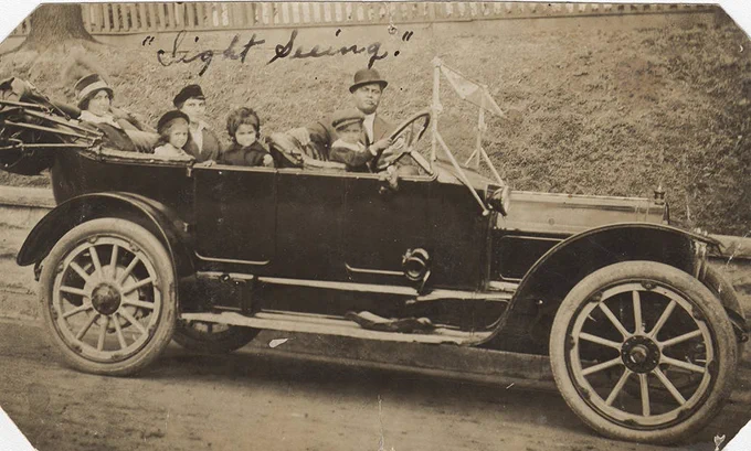 Jones family in car with "Sight Seeing" written at top, child holding steering wheel