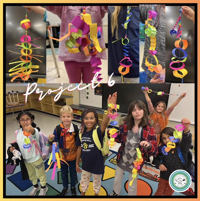 Kids hold up their colorful paper mobile sculptures.